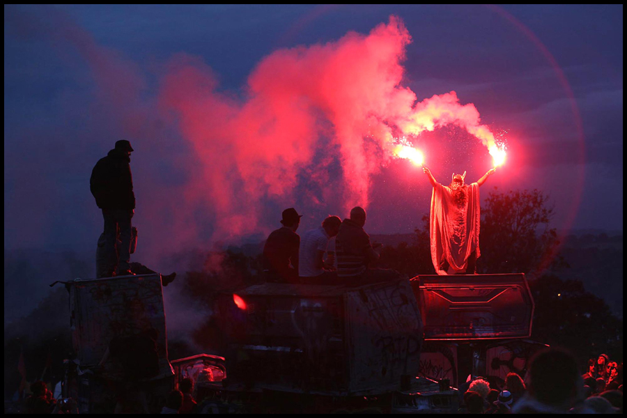 Revellers enjoy the sunset around the stone circle at Glastonbury Festival